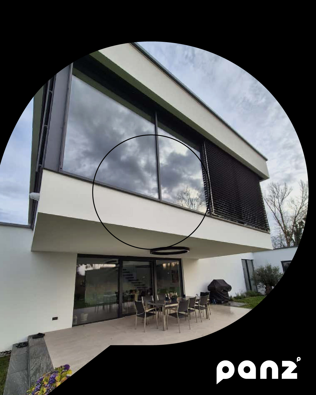 Detailaufnahme einer auskragenden Fassade mit Panoramafenstern, integrierten Raffstores und Blick auf die überdachte Terrasse.