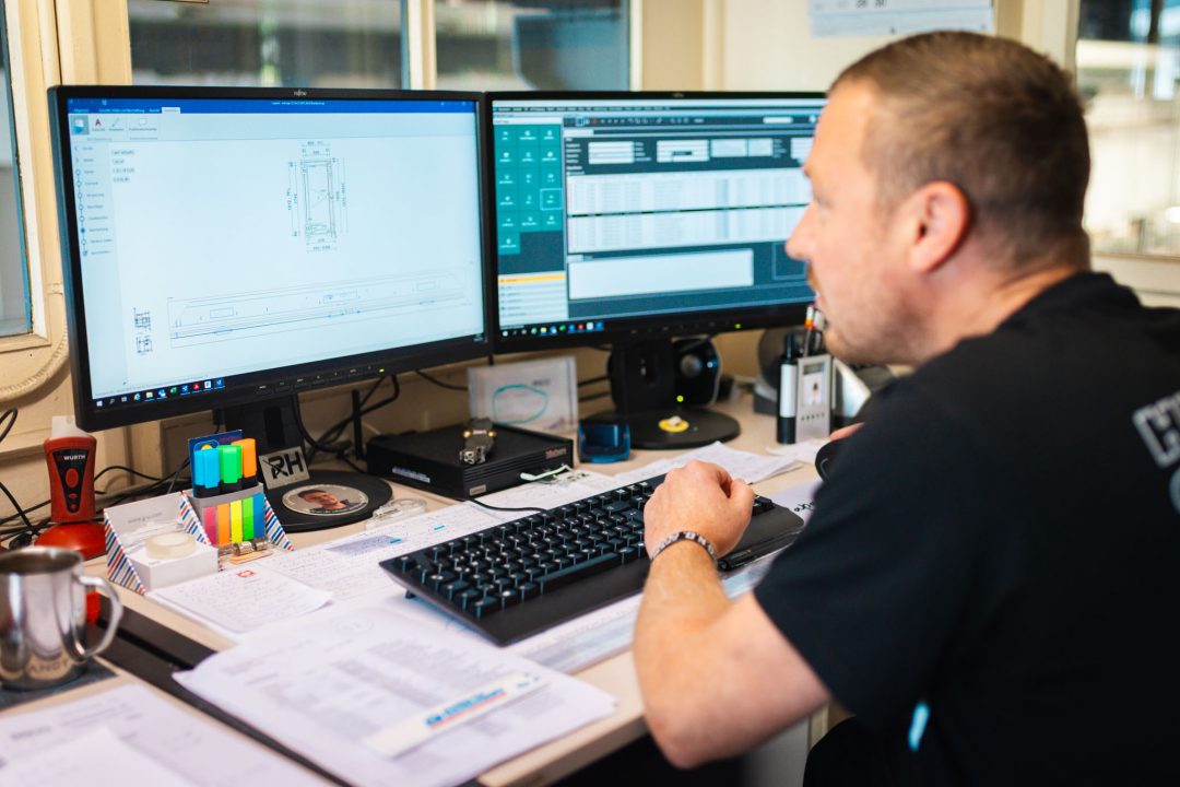 Ein Mitarbeiter bei der präzisen CAD-Planung einer Türkonstruktion an einem modernen Doppelmonitor-Arbeitsplatz bei Panz Aluminiumtechnik.